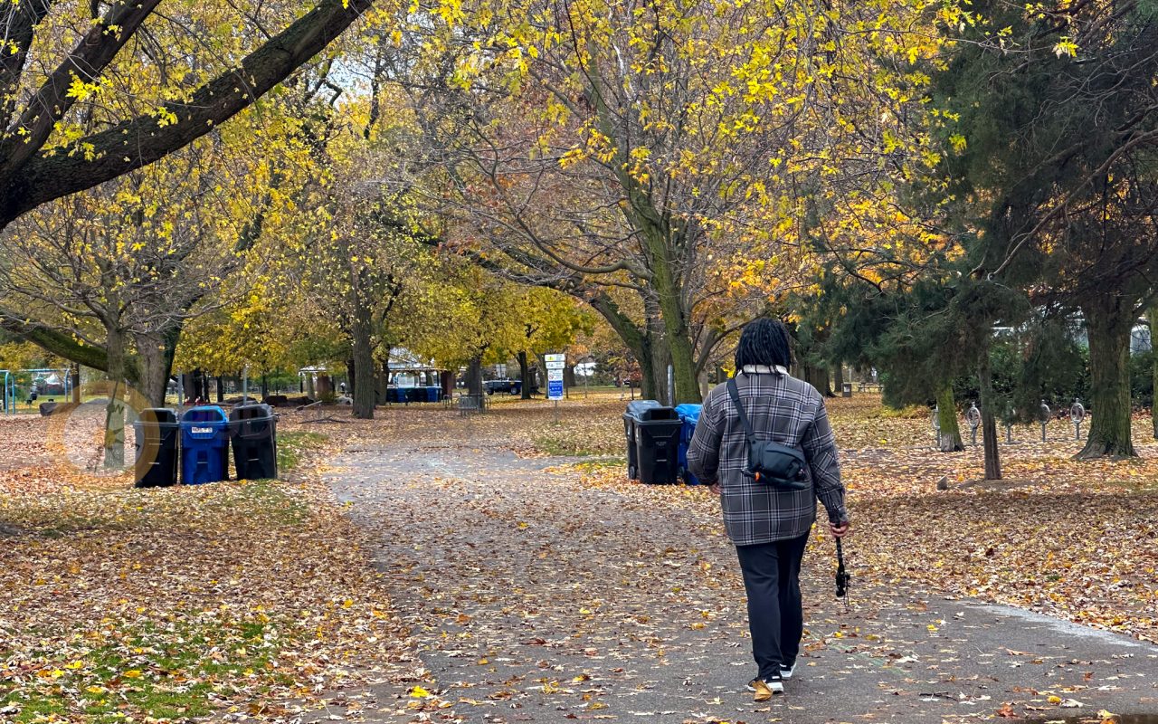 a woman walking on a path with trees and trash cans - best trails in toronto