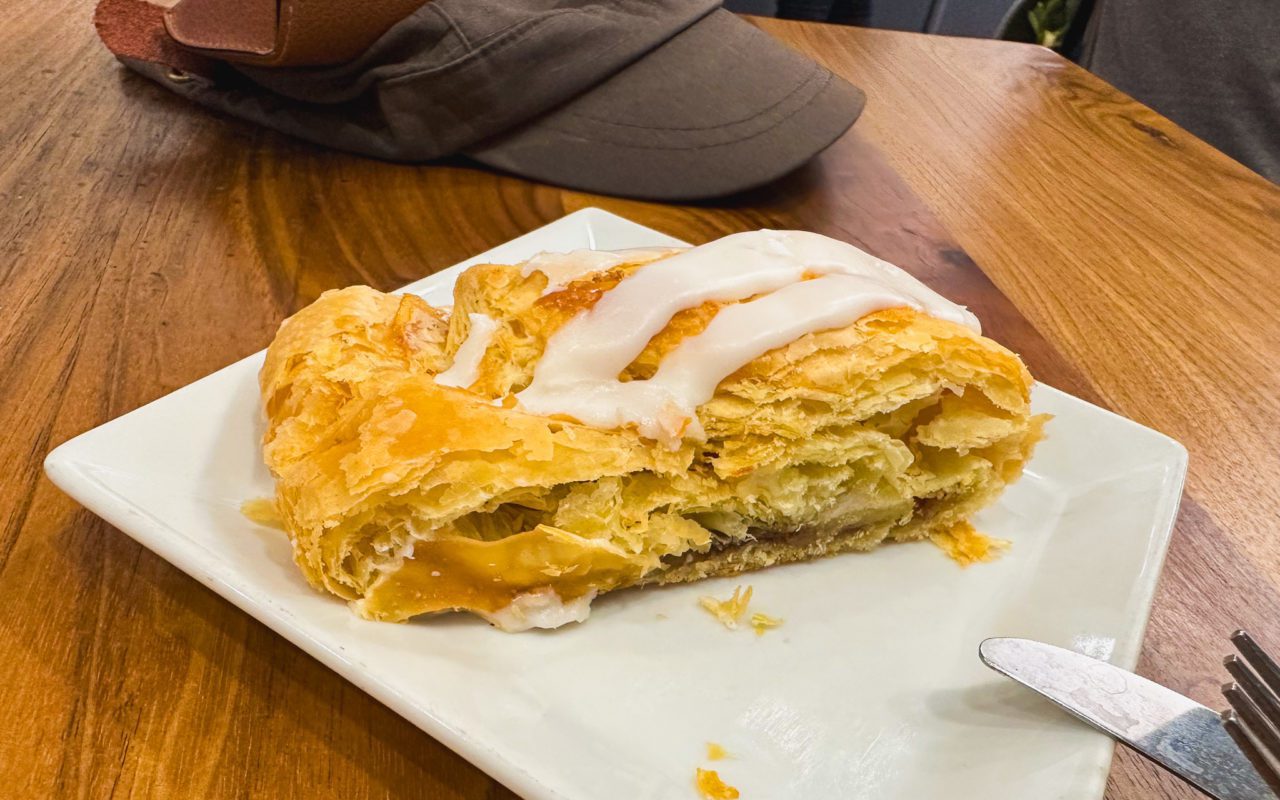 a half-eaten apple strudel with icing on a square white plate