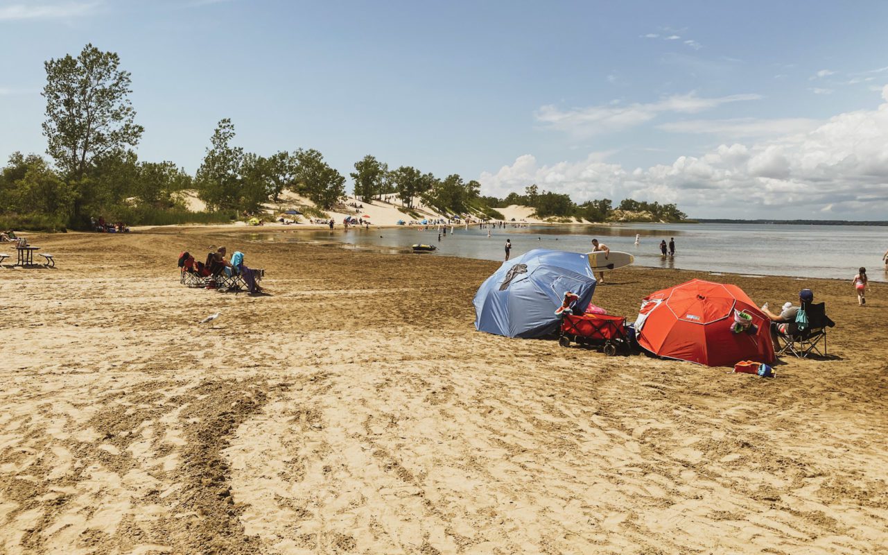 several people on the beach on a sunny day | best road trips from toronto
