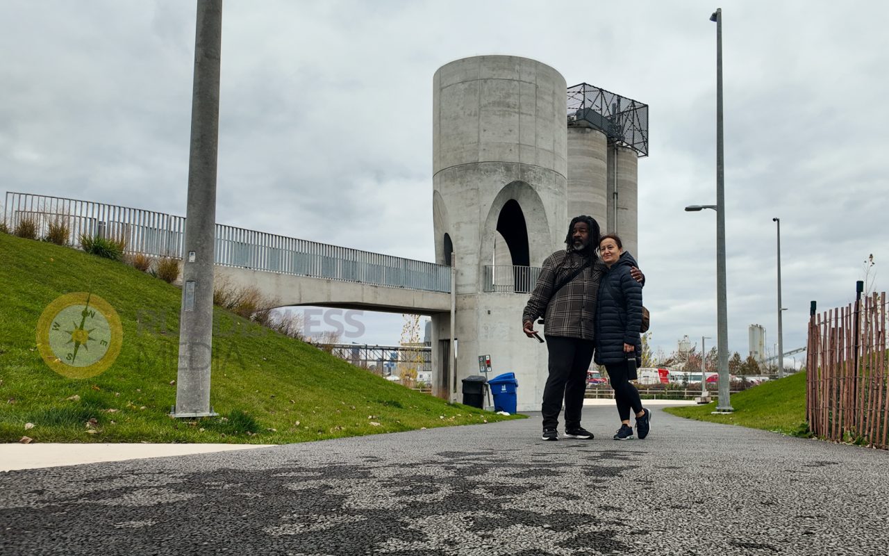 a couple of people standing on a path with a concrete structure - martin goodman