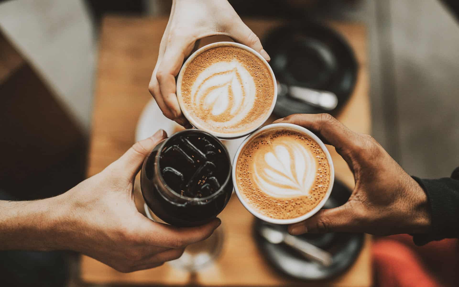 Three hands holding coffee drinks in a cheers | things to do in Almonte, Ontario