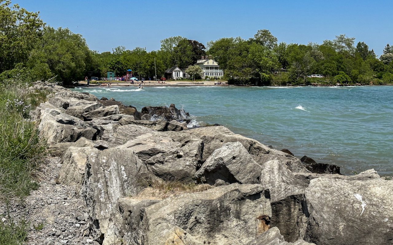 rocky shoreline overlooking a lake with a building in the distance on the opposite shore