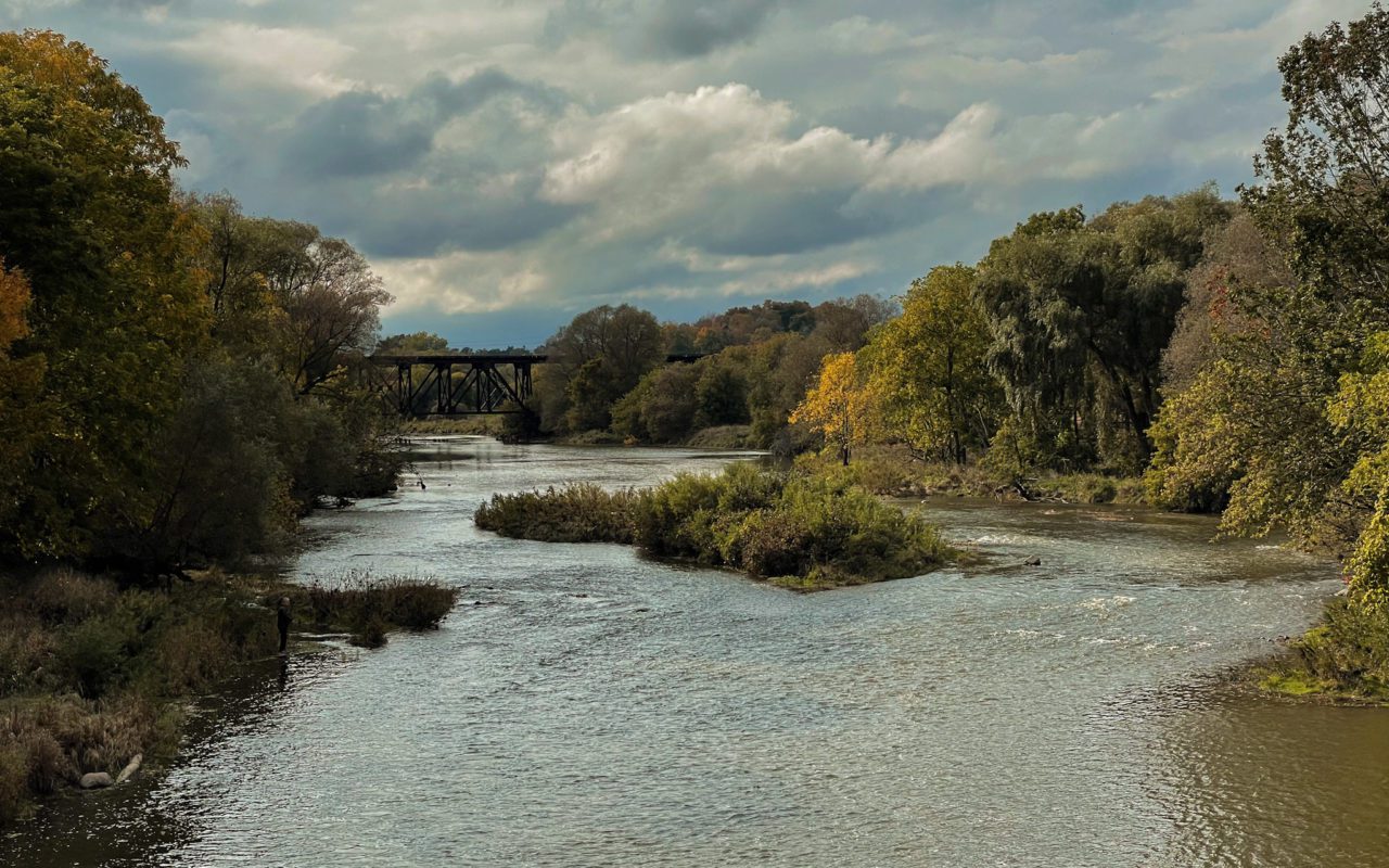Landscape view of a river surrounded by trees and a bridge in the distance | things to do in st jacobs ontario