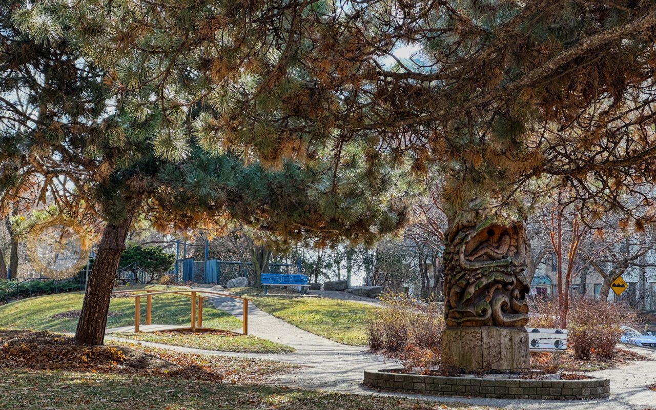 a tree trunk with a carved sculpture in the middle of a park - waterfront trail toronto