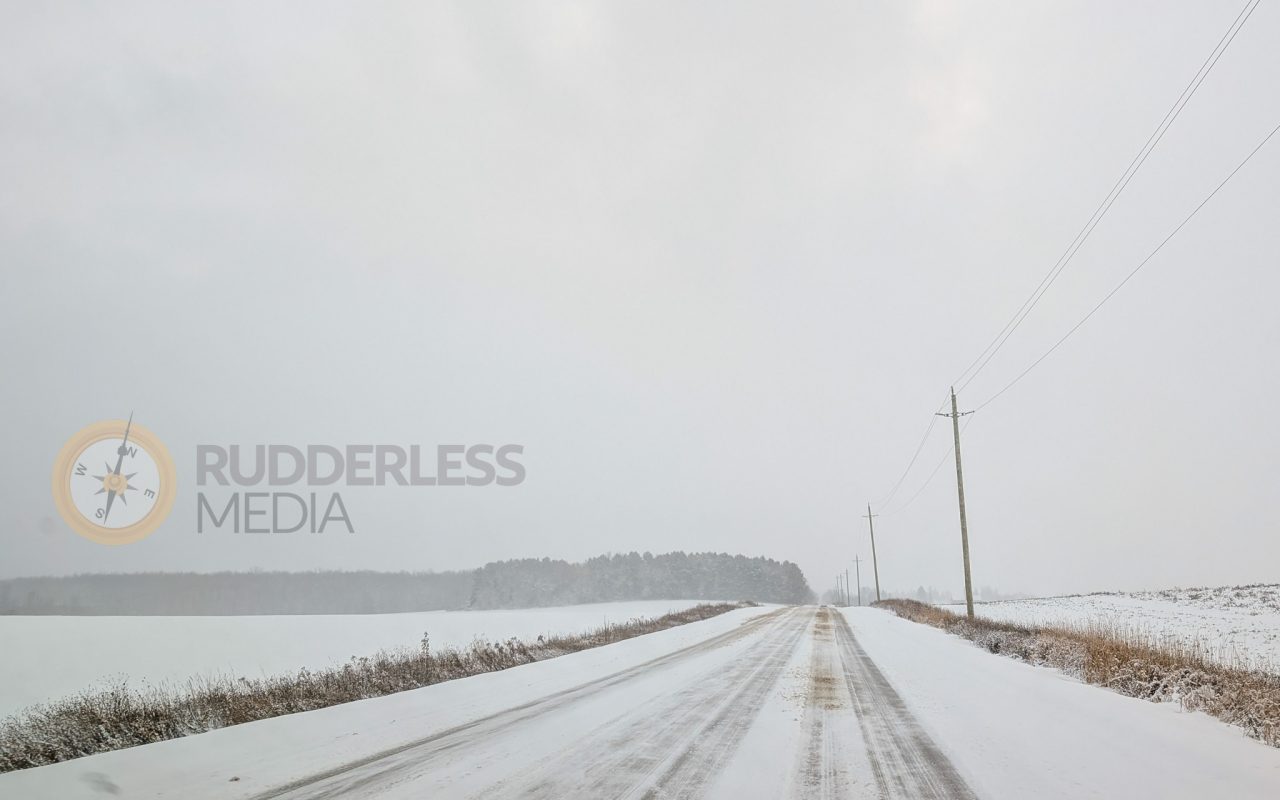 a snowy road with power lines and trees - winter road trip essentials
